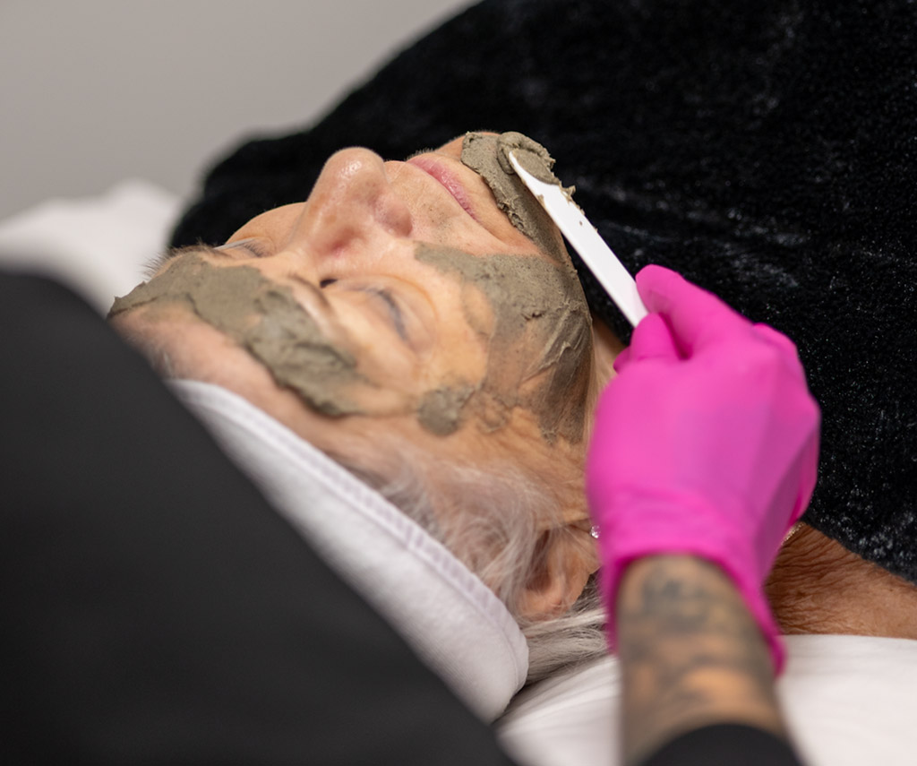 Application d’un masque de soin au pinceau sur le visage.